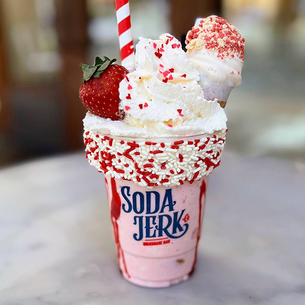 Strawberry Shortcake Lucky You Killer Shake in a Soda Jerk cup surrounded by Lucky Charms cereal.