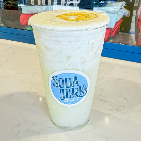 Liberty Cheesecake Killer Shake in a Soda Jerk cup surrounded by fresh fruit and a bottle of milk.