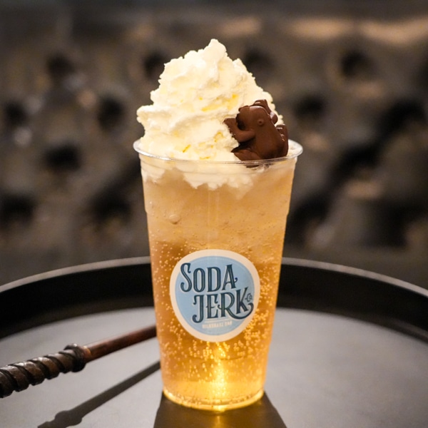 Deathly Swallows Whiz Bang Soda in a Soda Jerk cup next to a wizard's wand.