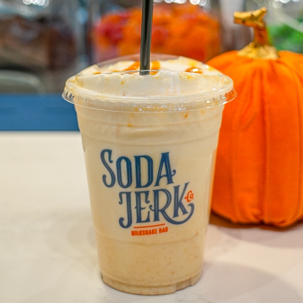 Pumpkin Caramel Milk in a Soda Jerk cup next to a stuffed pumpkin.