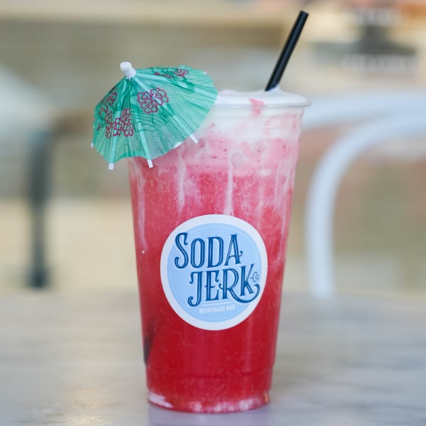 Strawberry Colada soda in a Soda Jerk cup with an umbrella on top.